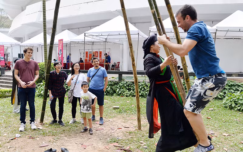 Du khách nước ngoài trải nghiệm trò chơi truyền thống tại Bảo tàng Dân tộc học Việt Nam (TP Hà Nội). Ảnh: MỸ HÀ