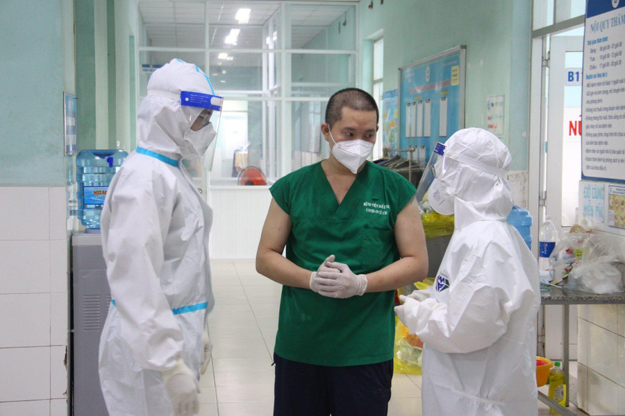 Vợ chồng bác sĩ Phương Dung và Hữu Hoàng trao đổi công việc trong khu điều trị với tình nguyện viên F0. Ảnh: Trần Tiến