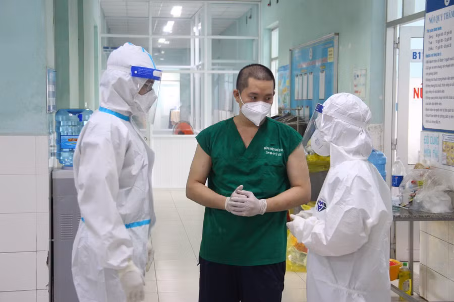 Vợ chồng bác sĩ Phương Dung và Hữu Hoàng trao đổi công việc trong khu điều trị với tình nguyện viên F0. Ảnh: Trần Tiến