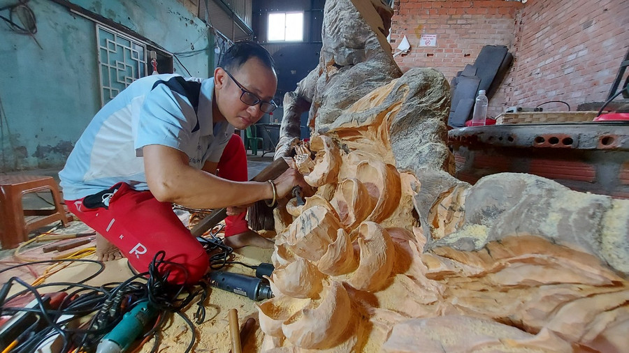 Anh Trần Đức Vinh đang cặm cụi sáng tạo nghệ thuật từ gỗ lũa. Ảnh: Nguyễn Tú