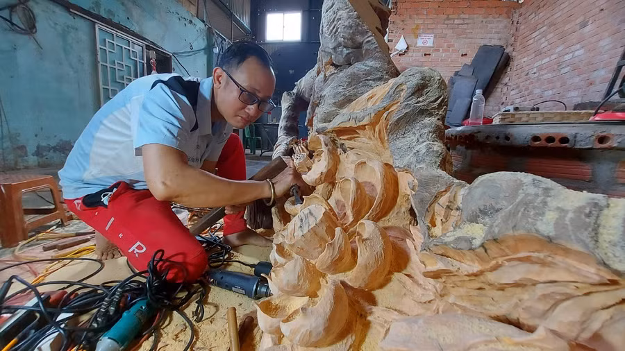 Anh Trần Đức Vinh đang cặm cụi sáng tạo nghệ thuật từ gỗ lũa. Ảnh: Nguyễn Tú