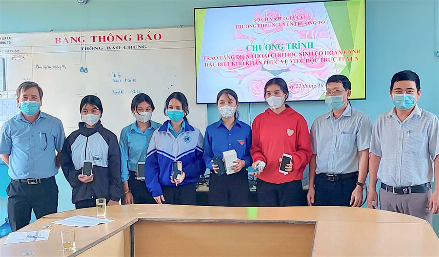 Em Rơmah H’Win (áo đỏ) cùng 4 học sinh có hoàn cảnh khó khăn của Trường THPT Nguyễn Trường Tộ (huyện Đức Cơ) phấn khởi nhận điện thoại do nhà trường trao tặng. Ảnh: Mộc Trà