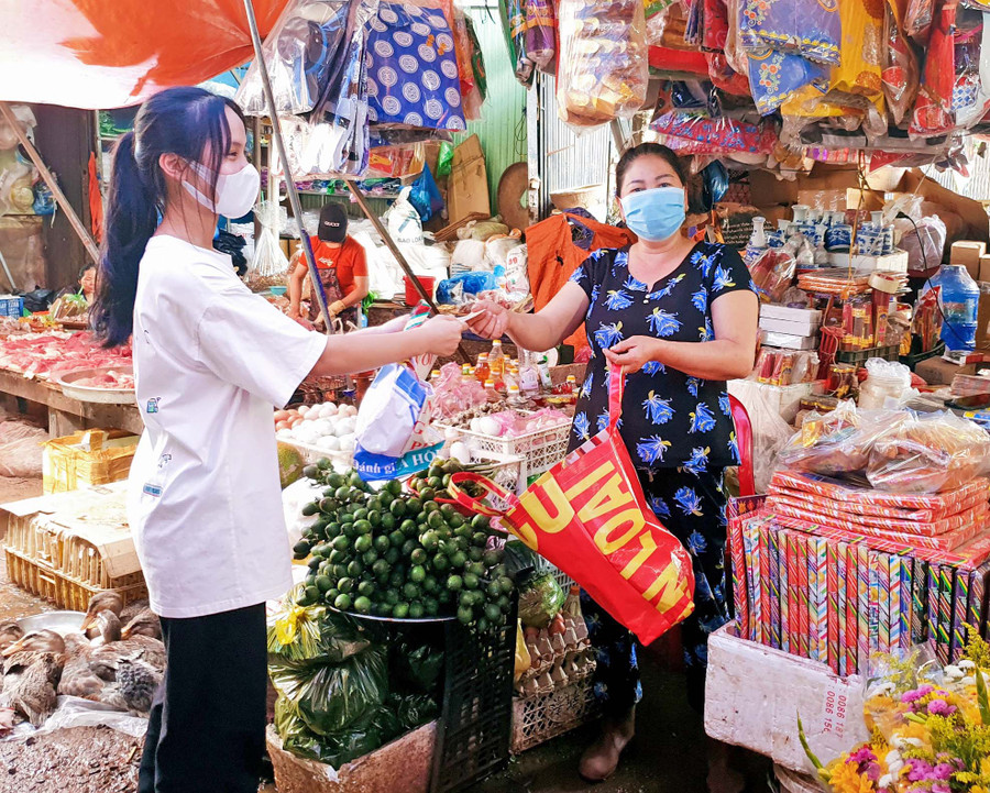 Em La Thị Mỹ Duyên (lớp 12A8, Trường THPT Nguyễn Bỉnh Khiêm) tặng túi đi chợ làm từ bạt hiflex cho tiểu thương ở chợ Chư Sê. Ảnh: Thủy Bình