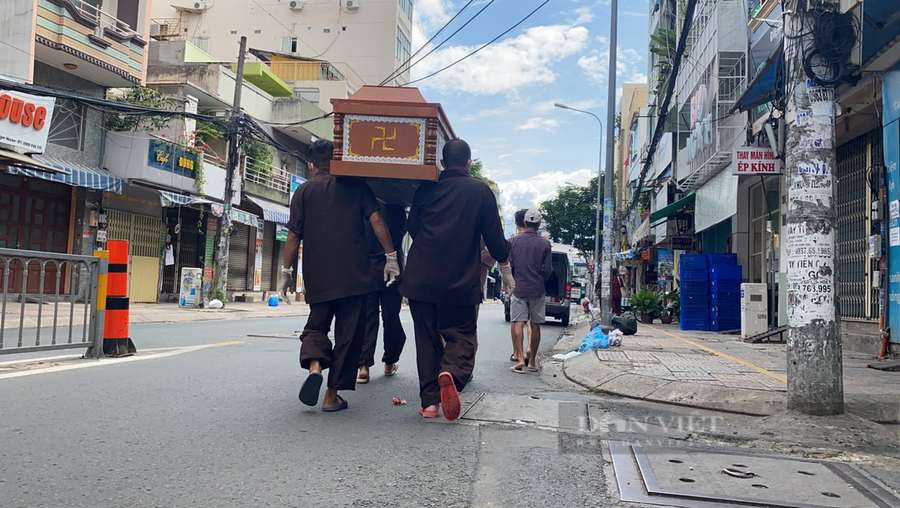 Các thành viên trong nhóm thiện nguyện khuân vác nạn nhân mất do Covid-19 ra xe đem đi mai táng. Ảnh: Chinh Hoàng