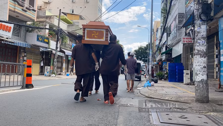 Các thành viên trong nhóm thiện nguyện khuân vác nạn nhân mất do Covid-19 ra xe đem đi mai táng. Ảnh: Chinh Hoàng