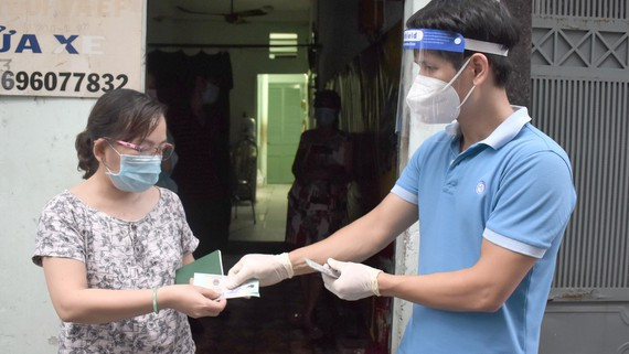 Cán bộ phường 12 quận 3 trao tiền hỗ trợ đợt 3 cho người dân khó khăn do ảnh hưởng của dịch Covid-19. Ảnh: Đình Lý