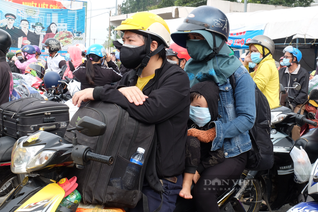  Người lao động rời Đồng Nai, gồng gánh cả gia đình về quê, có cả những em bé lọt thỏm trong lòng mẹ. Ảnh: Nha Mẫn