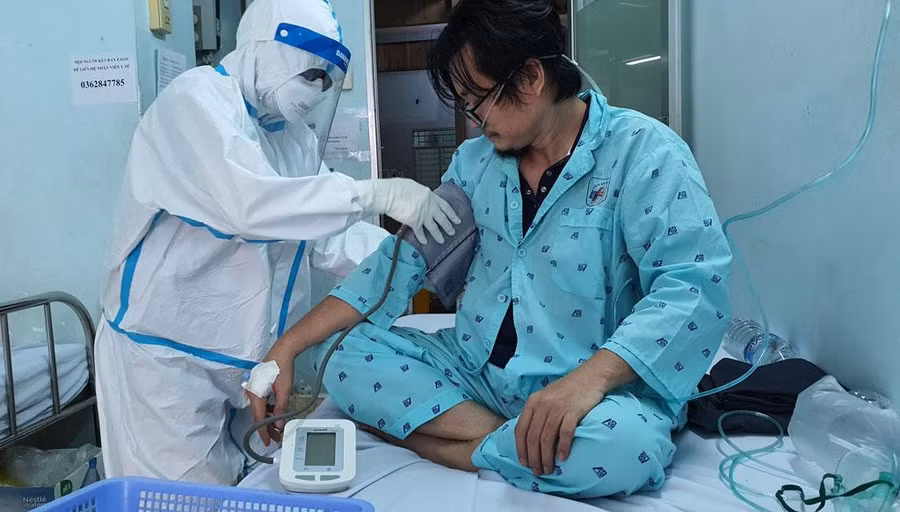 Điều dưỡng Bùi Thị Tỉnh kiểm tra tình trạng sức khỏe của bệnh nhân Covid-19. Ảnh: Bích Ngân