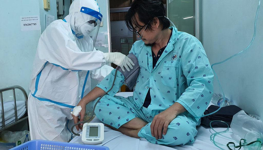 Điều dưỡng Bùi Thị Tỉnh kiểm tra tình trạng sức khỏe của bệnh nhân Covid-19. Ảnh: Bích Ngân