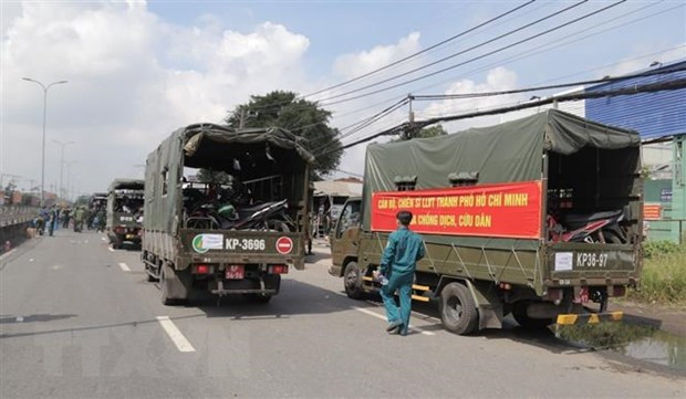 Lực lượng kiểm soát quân sự vận chuyển xe máy cho người dân lên xe ôtô chở về quê. (Ảnh: TTXVN phát)