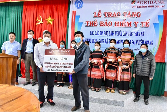 Đại diện Ngân hàng Nông nghiệp và Phát triển nông thôn chi nhánh Gia Lai (bên phải) trao biểu trưng tặng 100 thẻ BHYT cho học sinh dân tộc thiểu số trên địa bàn huyện Kbang. Ảnh: Như Nguyện