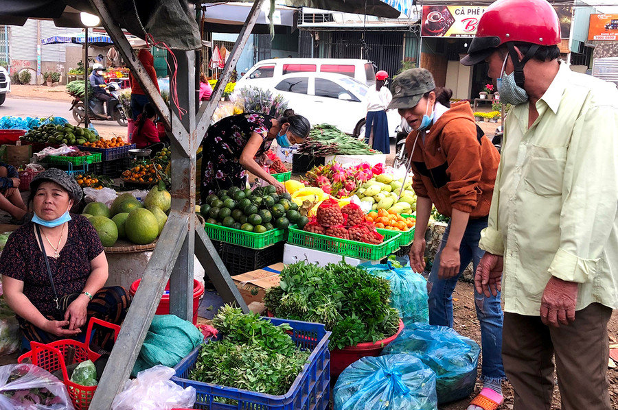 Bà Cù Thị An (bìa trái) bán rau ở chợ. Ảnh: Đinh Yến
