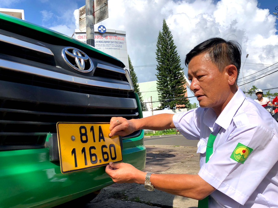 Tài xế của hãng Taxi Mai Linh lắp biển số nền vàng cho xe taxi. Ảnh: Lê Hòa
