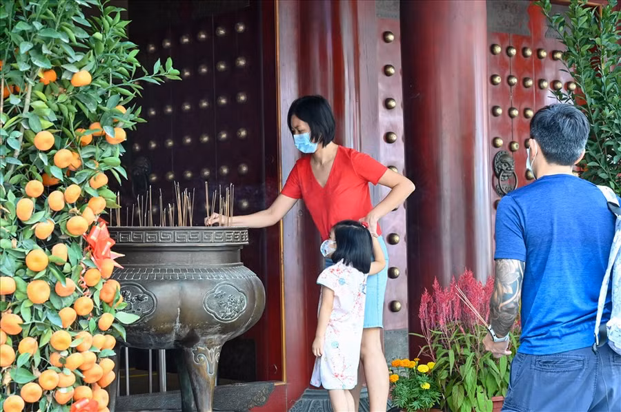 Một phụ nữ thắp hương cầu nguyện tại chùa ngày 29 Tết Nhâm Dần 2022 (ngày 31.1.2022) tại khu Chinatown ở Singapore. Ảnh: AFP