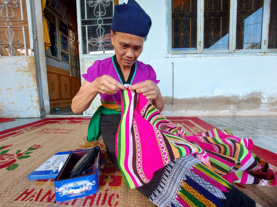 Bà Lương Thị Mắng chỉnh sửa hoa văn cho bộ trang phục của phụ nữ Thái. Ảnh: Thiên Di