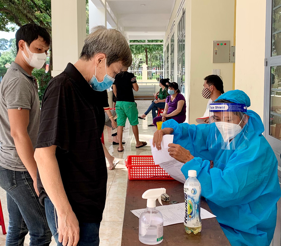  Người dân khai báo y tế trước khi tiêm vắc xin phòng Covid-19. Ảnh: Như Nguyện