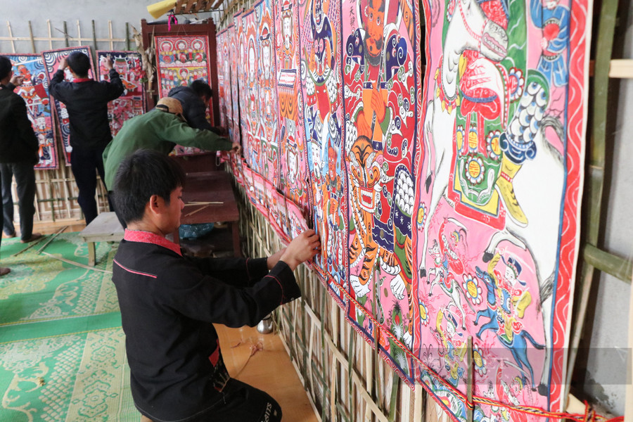 Dán giấy, treo tranh cần nhiều người trong họ giúp gia chủ. Ảnh Thanh Tuấn