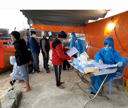 Cán bộ y tế của Tổ Kiểm soát phòng chống dịch Covid-19 đo thân nhiệt, hướng dẫn ngư dân khai báo y tế