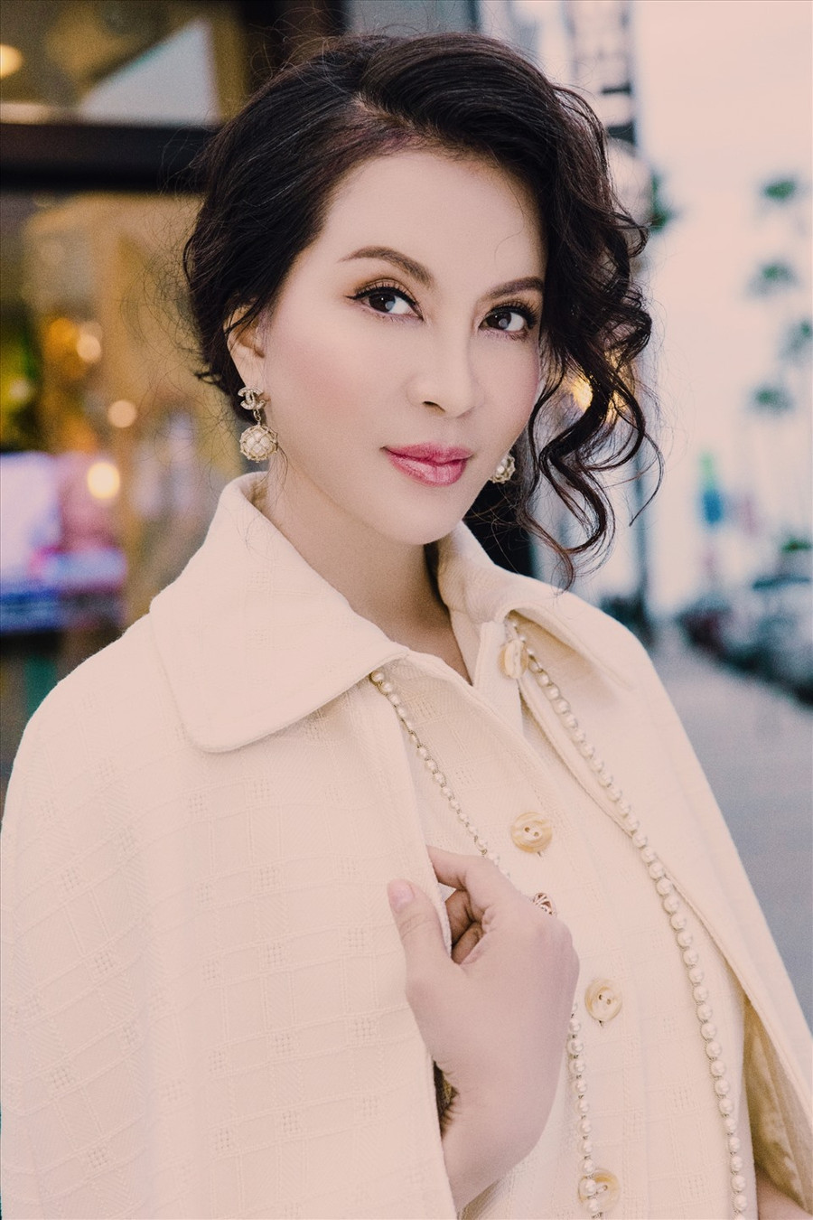 Mỹ nhân mặc suit trắng, đầm có họa tiết. Boots và áo khoác dáng dài giúp cô tăng sự quý phái. Để hoàn thiện phong cách, cô chọn búi tóc thấp, để hờ vài lọn tóc xoăn một bên làm điểm nhấn.