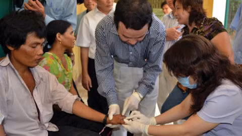 Bộ trưởng Bộ Y tế Nguyễn Thị Kim Tiến (bên phải) kiểm tra bệnh nhân mắc bệnh lạ.