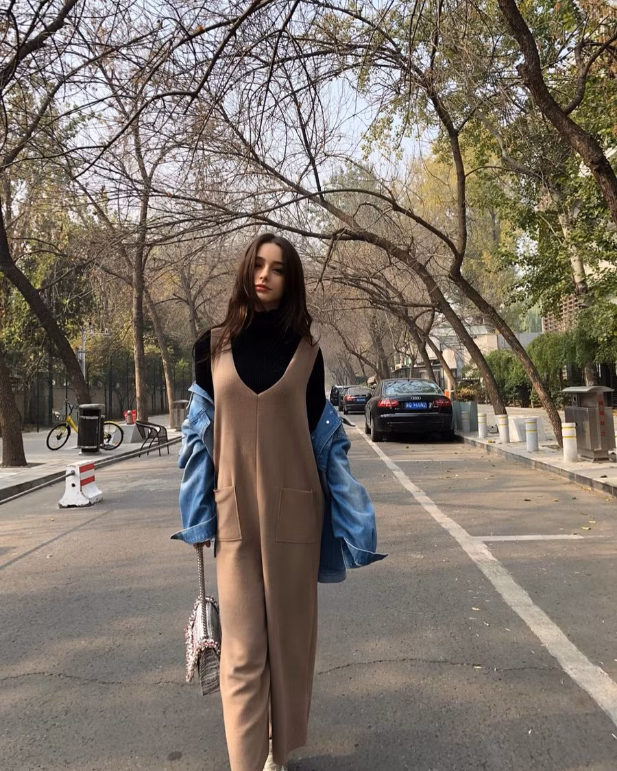 Nàng mẫu Nga mặc bộ jumpsuit màu nâu dáng hai dây to bản bên ngoài áo cổ lọ màu đen. Phối cùng với bộ đồ cô mặc áo khoác denim đeo túi xách. Với chiều cao 1m70 cô có thể tự tin mặc kiểu đồ dành cho người cao như thế này.