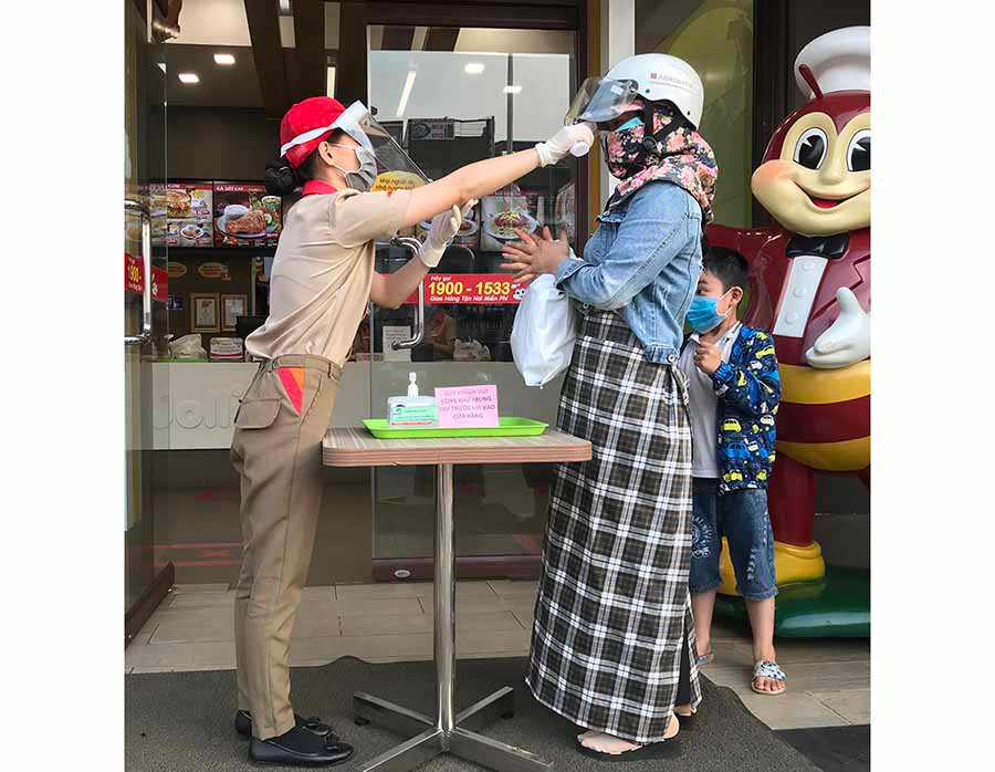  Cửa hàng Jollibee luôn bố trí nhân viên túc trực để đo thân nhiệt và sát khuẩn tay cho khách hàng. Ảnh: V.T