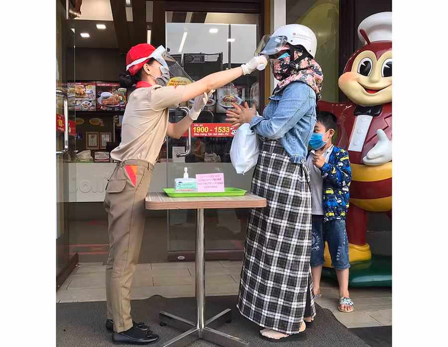  Cửa hàng Jollibee luôn bố trí nhân viên túc trực để đo thân nhiệt và sát khuẩn tay cho khách hàng. Ảnh: V.T