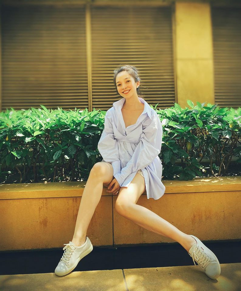Nữ ca sĩ diện chiếc áo sơ mi dáng dài kết hợp với giày thể thao ngồi tạo dáng khoe khéo đôi chân thon dài. 