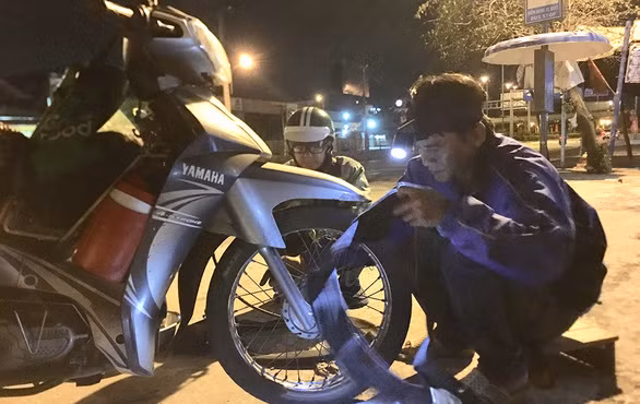 Thấy ruột xe đã mòn, anh Tùng thay luôn ruột mới tặng cho người xe ôm công nghệ vất vả mưu sinh đêm khuya - Ảnh: MY LĂNG