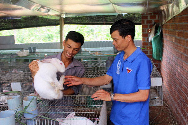 Anh Trần Văn Thế (bìa trái) chia sẻ kinh nghiệm nuôi thỏ cho cán bộ Đoàn xã Ia Bă. Ảnh: T.B