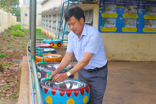 Thầy Nguyễn Trọng Ngoạn-Hiệu trưởng Trường Tiểu học thị trấn Phú Hòa bên những bồn rửa tay tái chế từ lốp xe để phục vụ học sinh trở lại trường. Ảnh: P.L Thầy Nguyễn Trọng Ngoạn-Hiệu trưởng Trường Tiểu học thị trấn Phú Hòa bên những bồn rửa tay tái chế từ lốp xe để phục vụ học sinh trở lại trường. Ảnh: P.L