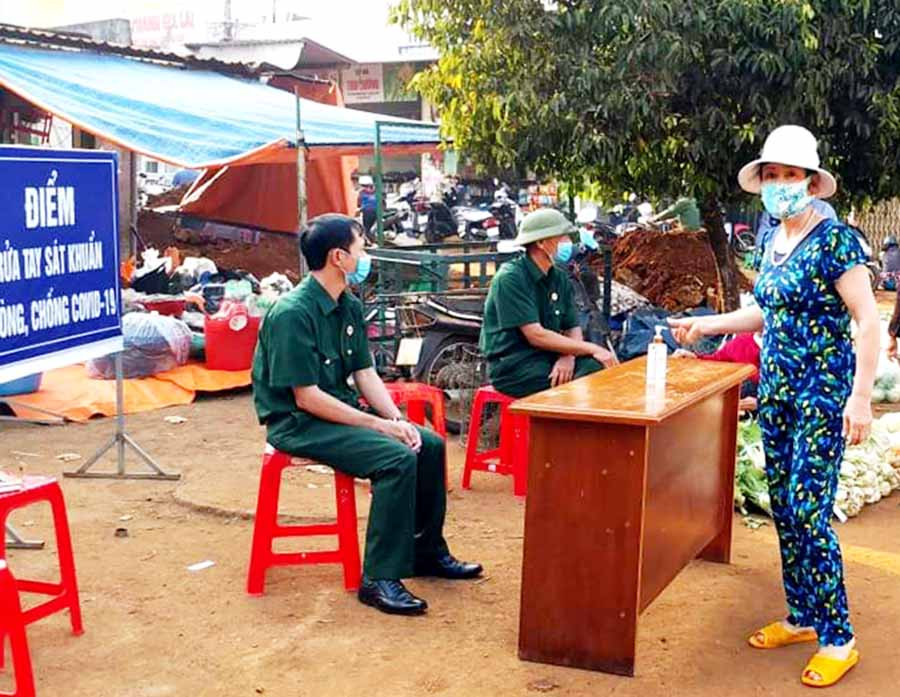 Hội Cựu chiến binh phường Đống Đa đặt chốt tại cổng chợ nhắc nhở người dân mang khẩu trang, rửa tay sát khuẩn. Ảnh: Minh Nguyễn