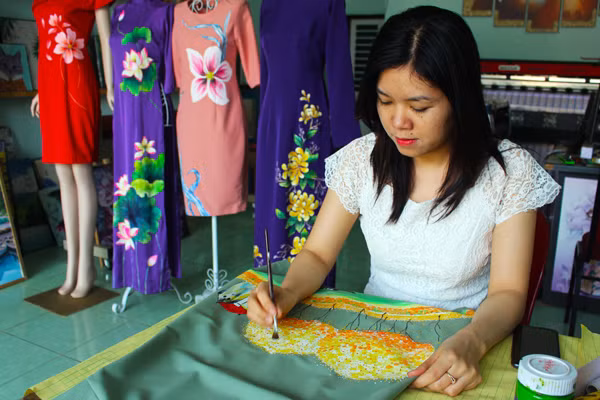 Chị Nguyễn Thanh Nhàn vẽ tranh lên trang phục để bán. Ảnh: P.L