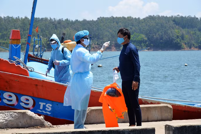 Lực lượng y tế kiểm tra thân nhiệt các ngư dân trên tàu QNg 90399 TS. Ảnh: T.Trực