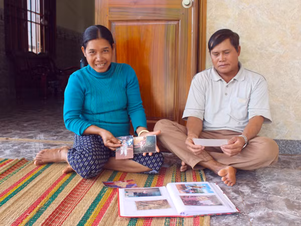  Vợ chồng ông Rơ Lan Hít và bà Rơ Châm Phêm xem lại những hình ảnh thuở nhỏ của 2 con gái nuôi. Ảnh: T.B
