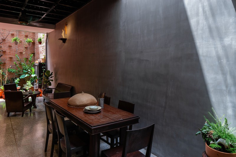 Tường bê tông không sơn trét phù hợp với màu sắc của bàn ghế gỗ.