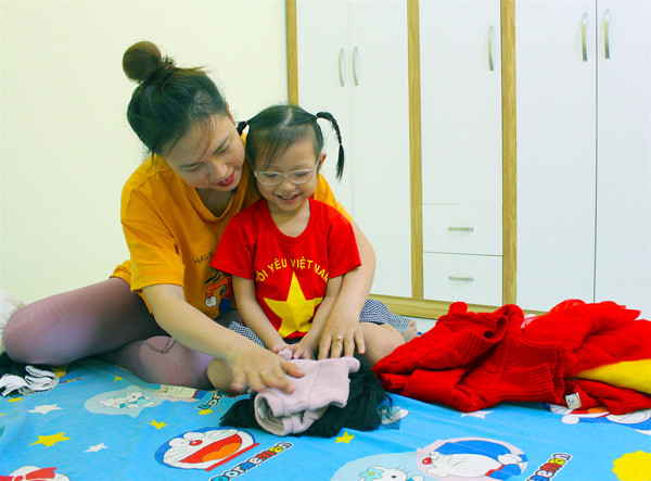 Chị Trần Vũ Thị Thanh Hoa (phường Thống Nhất, TP. Pleiku) hướng dẫn con gái kỹ năng tự xếp quần áo của mình và em gái. Ảnh: M.T