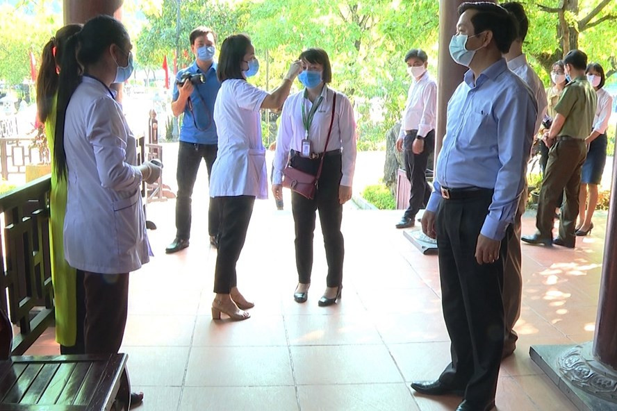 Nhân viên y tế tại Khu du lịch sinh thái Tràng An tiến hành kiểm tra sức khỏe và đo thân nhiệt đối với khách tham quan và nhân viên phục vụ. Ảnh: NT