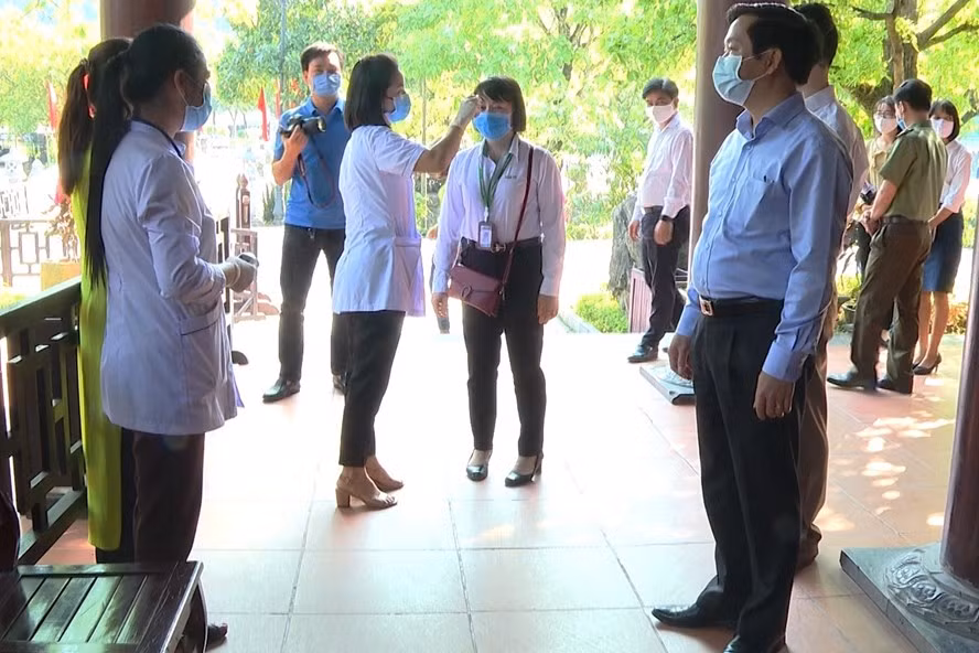 Nhân viên y tế tại Khu du lịch sinh thái Tràng An tiến hành kiểm tra sức khỏe và đo thân nhiệt đối với khách tham quan và nhân viên phục vụ. Ảnh: NT