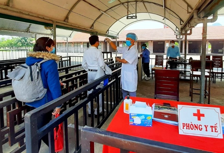 Nhân viên y tế kiểm tra sức khỏe và đo thân nhiệt đối với khách tham quan tại chùa Bái Đính. Ảnh: NT