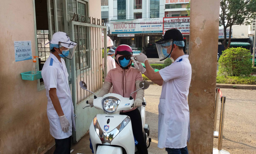 Nhân viên y tế- Bệnh viện Đa khoa tỉnh kiểm tra thân nhiệt cho người dân trước khi vào bệnh viện. Ảnh: Như Nguyện