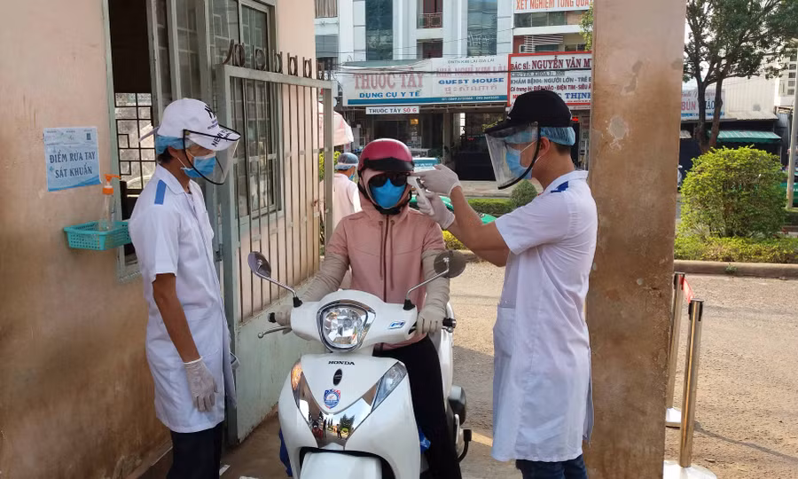 Nhân viên y tế- Bệnh viện Đa khoa tỉnh kiểm tra thân nhiệt cho người dân trước khi vào bệnh viện. Ảnh: Như Nguyện