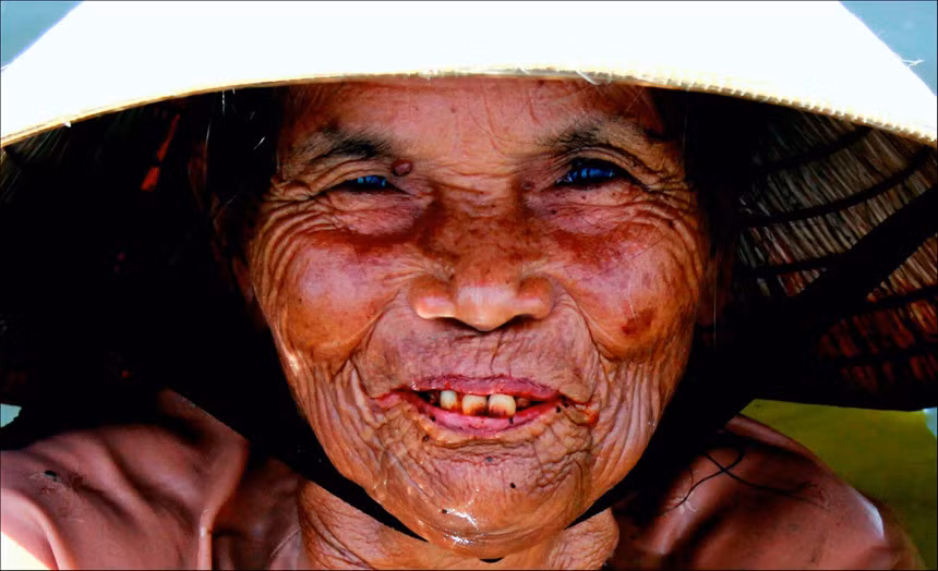 Nụ cười của một phụ nữ tại vùng phá Tam Giang (huyện Quảng Điền, Thừa Thiên - Huế). Dù phải ngâm mình nhiều giờ liền dưới nước lợ để bắt dậm trìa mưu sinh, một công việc nhọc nhằn và cô độc, nụ cười, ánh mắt yêu đời vẫn thường trực trên khuôn mặt khắc khổ của những người phụ nữ nơi đây. Ảnh: Hải Long.