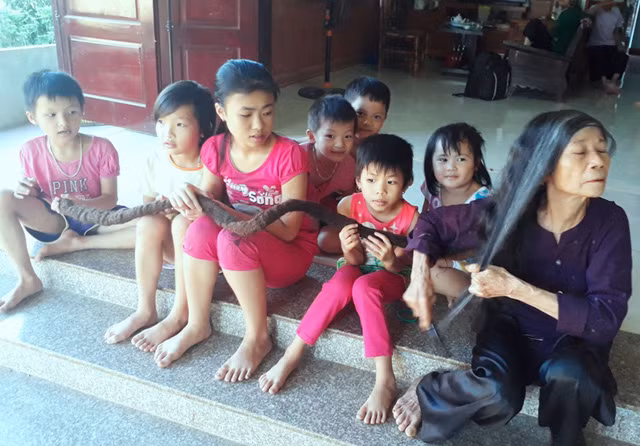 Các cháu nhỏ vui đùa bên mái tóc kỳ lạ của cụ Nghiên.