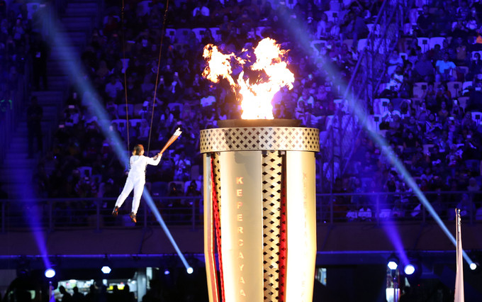...trước khi trao cho người châm vào tháp. Ngọn đuốc sẽ cháy suốt 12 ngày của Đại hội, nơi các VĐV tranh tài ở 38 môn với hơn 400 nội dung thi đấu.