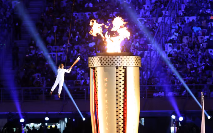 ...trước khi trao cho người châm vào tháp. Ngọn đuốc sẽ cháy suốt 12 ngày của Đại hội, nơi các VĐV tranh tài ở 38 môn với hơn 400 nội dung thi đấu.