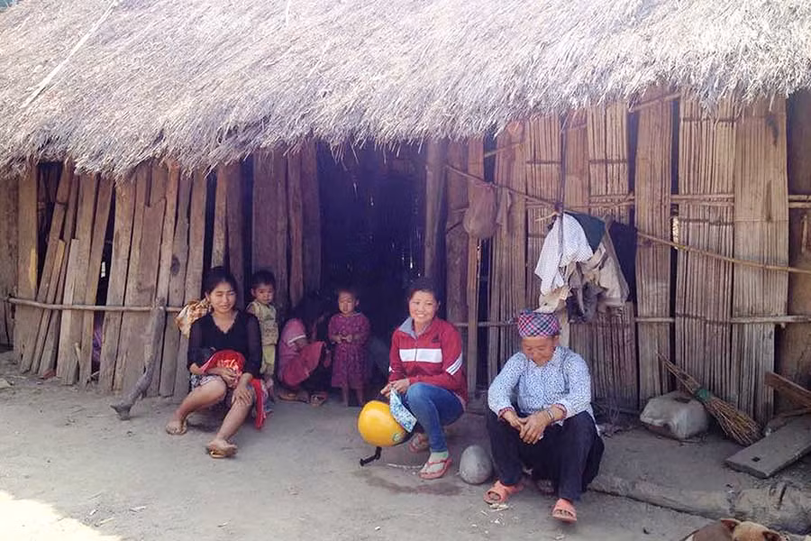 Chị Sùng Thị Pha (bìa trái, thôn Bình Lợi, xã Cư M’Lan, huyện Ea Súp) trước ngôi nhà tranh. Ảnh: Dạ Yến Thảo