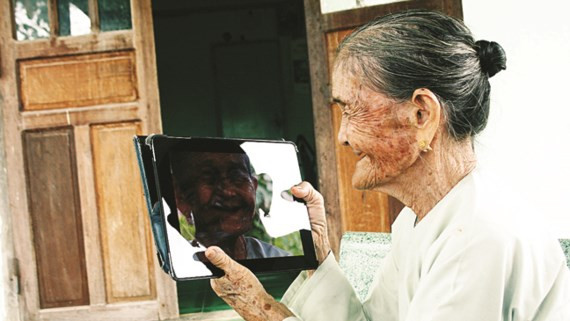 Bà mẹ Việt Nam anh hùng Võ Thị Tới nhìn chân dung mình trong iPad.