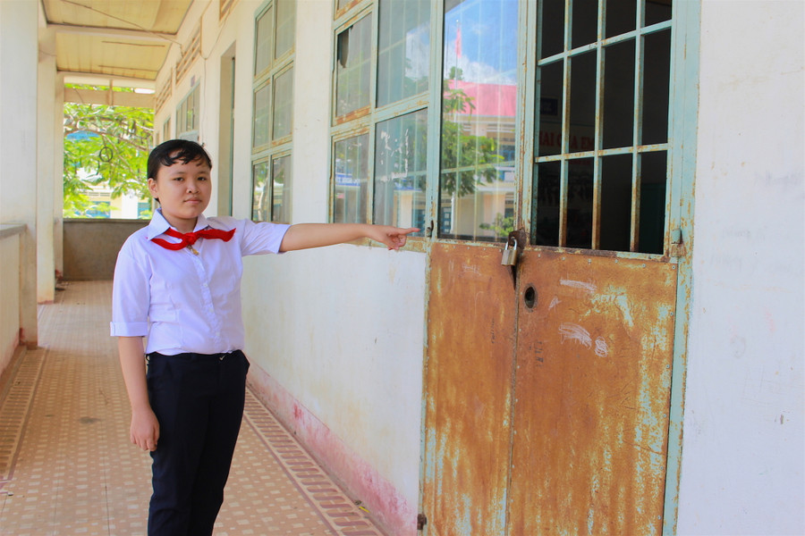Em Lê Thị Oanh bên lớp học đã xuống cấp ở trường cũ. Ảnh: Mộc Trà