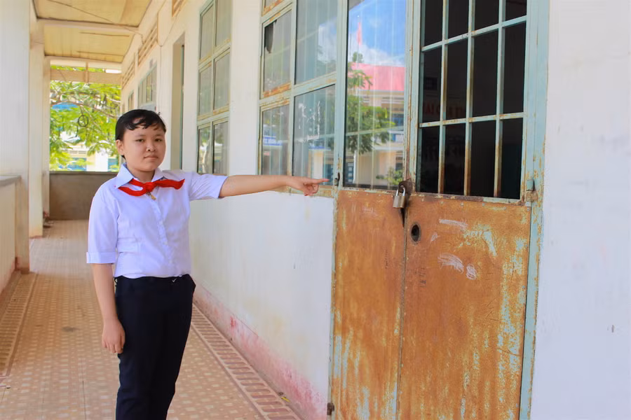 Em Lê Thị Oanh bên lớp học đã xuống cấp ở trường cũ. Ảnh: Mộc Trà